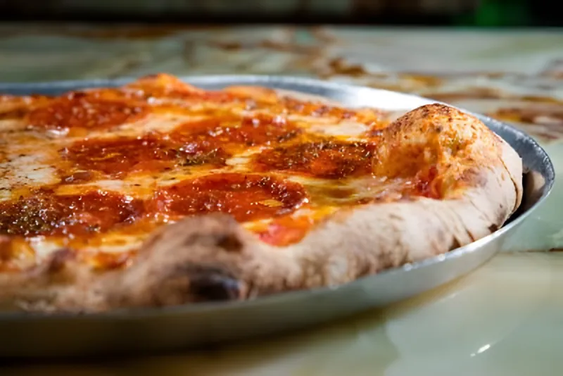 A Diavola pizza on its tray, thin pepperoni edge to edge