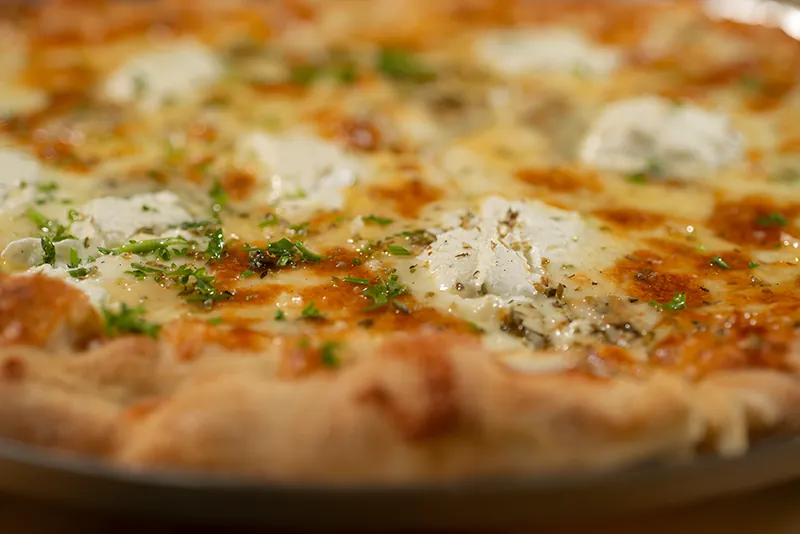 Close view of a white four-cheese pizza with ricotta and gorgonzola, the crust blistered